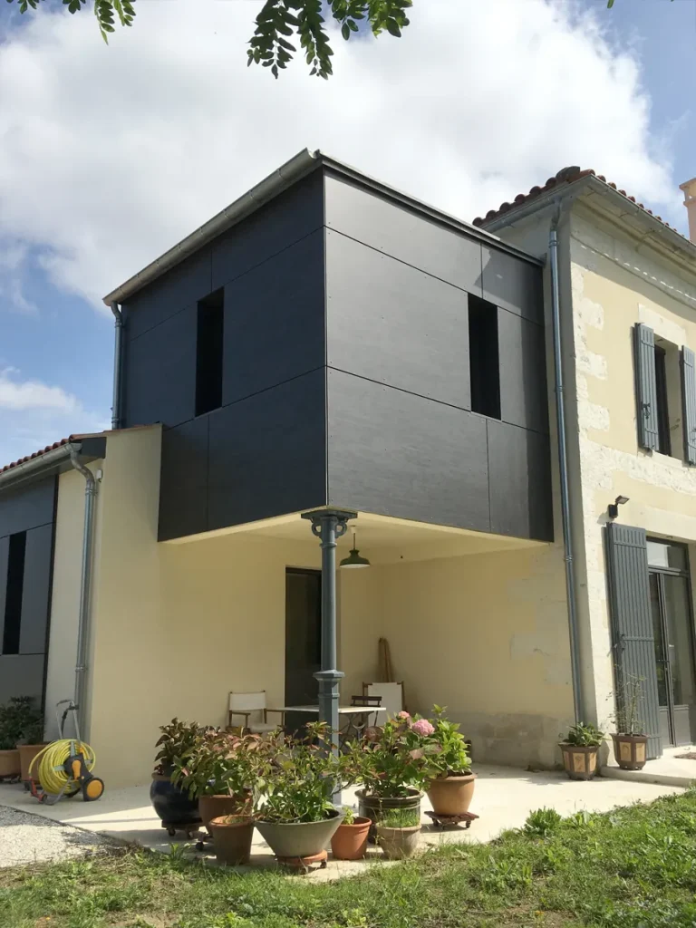 Extension à bardage noir accolée à une maison en pierre