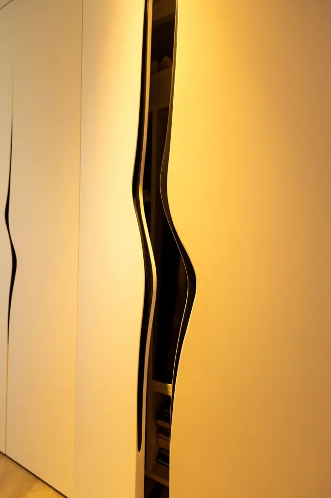 Détail d’un meuble sur mesure à découpe ondulée et éclairage intégré